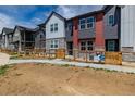 Modern townhome exteriors feature unique color schemes and a small fenced yard at 2877 E 103Rd Dr, Thornton, CO 80229