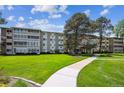 Spacious condo building with well-maintained lawn and mature trees, set against a blue sky at 725 S Alton Way # 7D, Denver, CO 80247