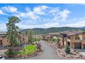 Scenic street view of modern homes with lush landscaping and mountain backdrop under a blue sky at 756 Dreamcatcher Ln, Evergreen, CO 80439