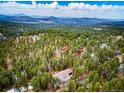 Breathtaking aerial view of a secluded home surrounded by lush forest and distant mountain ranges at 28254 Tresine Dr, Evergreen, CO 80439
