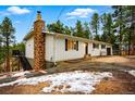 Cozy two-story home featuring a classic brick chimney and staircase to an upper level deck at 28254 Tresine Dr, Evergreen, CO 80439