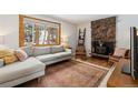 Cozy living room featuring a stone fireplace, comfortable sofa and a view of the trees at 28254 Tresine Dr, Evergreen, CO 80439
