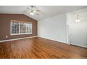 Spacious living room featuring vaulted ceilings, wood floors, abundant natural light, and a ceiling fan at 5210 Roadrunner Ave, Firestone, CO 80504