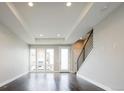 Light-filled living room with large windows, hardwood floors, tray ceiling, and adjacent staircase at 2858 W Parkside Pl, Denver, CO 80221