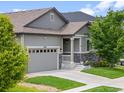 This exterior shot showcases the covered porch, beautiful stone accents, and well-kept lawn at 18036 E 99Th Ave, Commerce City, CO 80022