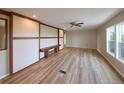 Bright living room with wood flooring, built-in bench, ceiling fan, and large windows for natural light at 11595 Pass Me By Rd, Strasburg, CO 80136