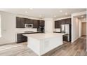 Modern kitchen featuring stainless steel appliances, a large island with a white countertop, and dark cabinetry at 635 Twilight St, Erie, CO 80516