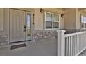 Close-up of front door and porch with stone accent, house numbers and exterior lighting at 4714 Carmichael Ct, Brighton, CO 80603