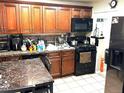 Well-lit kitchen featuring warm wood cabinetry, black appliances, and a tile backsplash, and stone dining table at 4411 W Center Ave, Denver, CO 80219