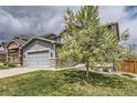 Lovely two-story home with a blooming tree in the yard, a gray garage, and stone accents at 11771 W Quarles Ave, Littleton, CO 80127