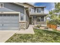 Inviting two-story home featuring a covered porch with stone pillars and a well-manicured lawn at 11771 W Quarles Ave, Littleton, CO 80127
