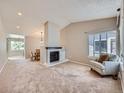 Bright living room featuring a fireplace, neutral carpet, and ample natural light at 31 Shetland Ct, Highlands Ranch, CO 80130