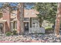 Inviting home exterior featuring a brick chimney and front entrance with stone landscaping at 14076 E Radcliff Cir, Aurora, CO 80015