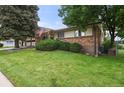 Well-kept front yard of a single Gathering home, featuring mature landscaping and an American flag at 8198 E Lehigh Dr, Denver, CO 80237