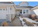 Front entrance of the home with a walkway, stone accents, and mature shrubs at 7879 S Zante Ct, Aurora, CO 80016