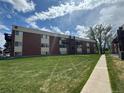 Lush lawn of brick apartment complex with walkways, landscaping, and building access at 3613 S Sheridan Blvd # 16, Denver, CO 80235
