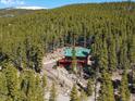 Secluded mountain cabin with a green roof surrounded by dense forest, providing privacy and stunning natural views at 451 Harris Dr, Idaho Springs, CO 80452
