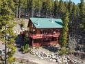 Cozy two-story cabin with a green roof nestled among trees, featuring a spacious deck for outdoor enjoyment at 451 Harris Dr, Idaho Springs, CO 80452