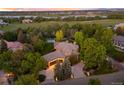 Aerial view of home with lush landscaping, long driveway, and lake views at 7050 S Polo Ridge Dr, Littleton, CO 80128