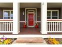 Inviting front porch with vibrant flowerpots flanking the red door and decorative columns at 5137 Mt Arapaho Cir, Frederick, CO 80504