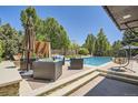 Outdoor patio with comfortable seating, umbrella, and hanging chair near a sparkling pool, ideal for relaxing and entertaining at 9470 S Silent Hills Dr, Lone Tree, CO 80124