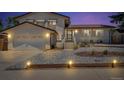 Charming home illuminated at dusk features manicured landscaping, a garage, and brick accents at 16941 E Eastman Pl, Aurora, CO 80013