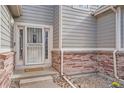 Close-up of the front entrance with a secure screen door and brick accents at 9306 W 13Th Pl, Lakewood, CO 80215