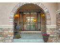 Close-up of a charming front entryway with stone archway and decorative metal gate, creating a welcoming feel at 6047 Vacquero Cir, Castle Pines, CO 80108