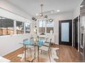 Bright dining area with modern chandelier and glass table, adjacent to an entryway and a door at 1260 Newton St # 1, Denver, CO 80204