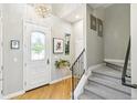 Bright entryway featuring beautiful hardwood floors, a modern chandelier, and staircase leading to the upper level at 7812 Inverness Blvd, Englewood, CO 80112