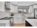 Updated kitchen features white cabinets, stainless steel appliances, and a stylish backsplash and countertops at 9565 W 12Th Pl, Lakewood, CO 80215