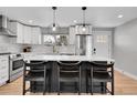 Modern kitchen features white cabinets, stainless steel appliances, quartz countertops, and an eat-in island at 9565 W 12Th Pl, Lakewood, CO 80215