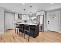 Bright kitchen with island seating, stainless appliances, white cabinetry, stylish pendant lighting, and light wood floors at 9565 W 12Th Pl, Lakewood, CO 80215