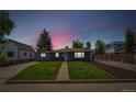 Charming home at dusk with a lush lawn, sidewalk and manicured landscape at 309 W Oak St, Lafayette, CO 80026
