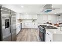 Open kitchen showcasing stainless steel refrigerator and stove, white cabinets and hardwood floors at 309 W Oak St, Lafayette, CO 80026