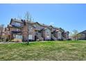 Exterior view of condos, showing balconies, stone accents, and green lawn at 2846 W Centennial Dr # E, Littleton, CO 80123