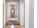 Inviting entryway featuring arched doorways, stone flooring, and a unique wooden door with decorative chandelier at 181 Race St, Denver, CO 80206