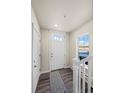 Bright entryway featuring a white front door with glass panels, and a gray rug on stylish hardwood floors at 350 High Point Dr # C201, Longmont, CO 80504