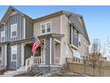 Two-story townhome with gray and beige siding, a front porch, and American flag at 2932 Low Meadow Blvd, Castle Rock, CO 80109