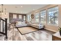 Spacious living room with L-shaped sofa, brick accent wall, and wood-look floors at 2932 Low Meadow Blvd, Castle Rock, CO 80109