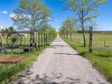 Long, gravel driveway lined with mature trees and rustic fencing leading to the property at 2610 W County Road 4, Berthoud, CO 80513