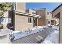 Inviting exterior shows a cozy home with a wooden walkway covered in snow on a sunny day at 6980 Fargo Trl, Littleton, CO 80125