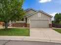 Charming single-Gathering home features a two-car garage, brick accents, a lush lawn, and mature trees at 386 Monte Vista St, Brighton, CO 80601