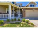 Inviting front porch with white pillars, well manicured landscaping, and brick accents at 16534 E Fire Fly Ave, Parker, CO 80134
