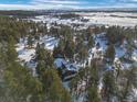 Aerial view of a home nestled in a winter wonderland, surrounded by trees and snow-covered landscapes at 9142 Warriors Mark Dr, Franktown, CO 80116