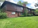 Spacious backyard featuring lush green grass, trees, and a brick and wood exterior at 12075 W 18Th Dr, Lakewood, CO 80215