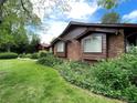 Close up of a single story home with brick and wood exterior and a green lawn at 12075 W 18Th Dr, Lakewood, CO 80215