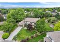Aerial view of a home with mature trees, a large lawn, landscaping, and mountain views in the distance at 5185 W Fair Pl, Littleton, CO 80123