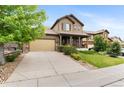 View of a home with a covered porch, large driveway, well-kept landscaping, and tan exterior at 10546 Sundial Rim Rd, Highlands Ranch, CO 80126
