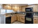 Kitchen with wood cabinets, black appliances, and tile backsplash at 1869 S Union Blvd, Lakewood, CO 80228